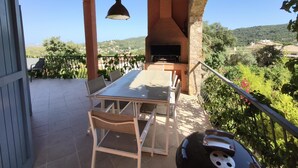 An outdoor patio with a table and chairs, a grill, and a view of the countryside. - Los Palmitos, Calonge - Costa Brava (Calonge)
