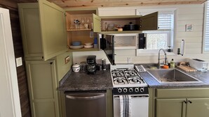 A compact kitchen with a stove, microwave, and sink.