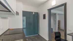 A modern kitchen with a built-in oven, a glass door cabinet, and a black chair. - GuestHost - Charming Apartment in Venice Mestre (Venezia)