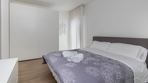 A modern hotel room with a large bed, a wardrobe, and a bedside table. - GuestHost - Charming Apartment in Venice Mestre (Venezia)