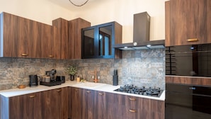 A modern kitchen with dark wood cabinets, a white countertop, a gas stove, and a black oven.