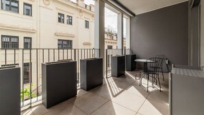 Un balcon avec une table et des chaises, une balustrade et une vue sur les bâtiments.