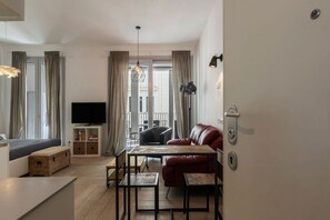 A modern living room with a sofa, a coffee table, a TV, and a dining area.