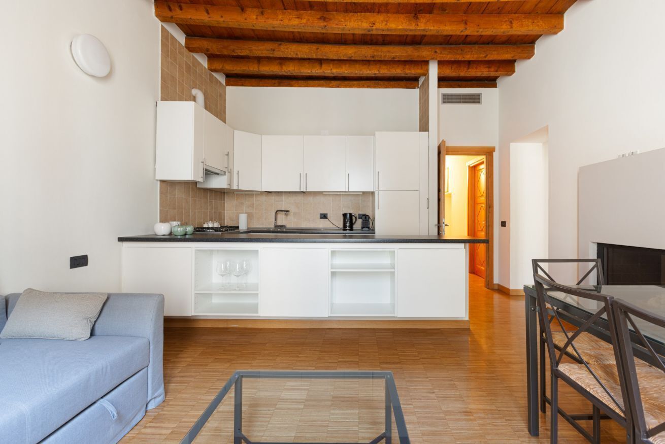 A compact kitchen with white cabinets, a wooden ceiling, and a dining area with a table and chairs.