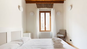 Une chambre à coucher avec un lit, une chaise, une fenêtre avec des rideaux et un radiateur.