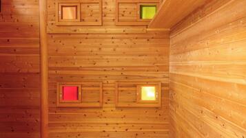 A wooden cabin interior with a sloped ceiling and three small windows.