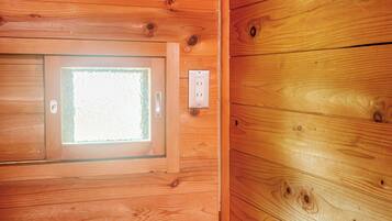 A wooden cabin interior with a window, a door, and an electrical outlet.