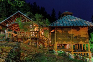 Eine Holzhütte mit einer Treppe, die zu einer Terrasse führt, umgeben von Bäumen.