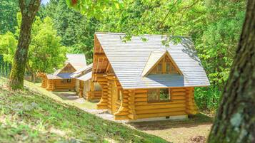 Eine Reihe von Blockhütten mit Satteldächern, umgeben von dichtem Wald.