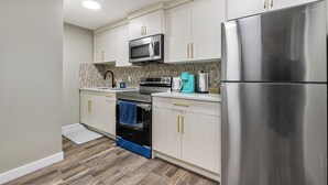 A modern kitchen with stainless steel appliances, light-colored cabinetry, and a patterned backsplash.
