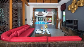 A modern living room with a red sofa, a television, and a pool view.