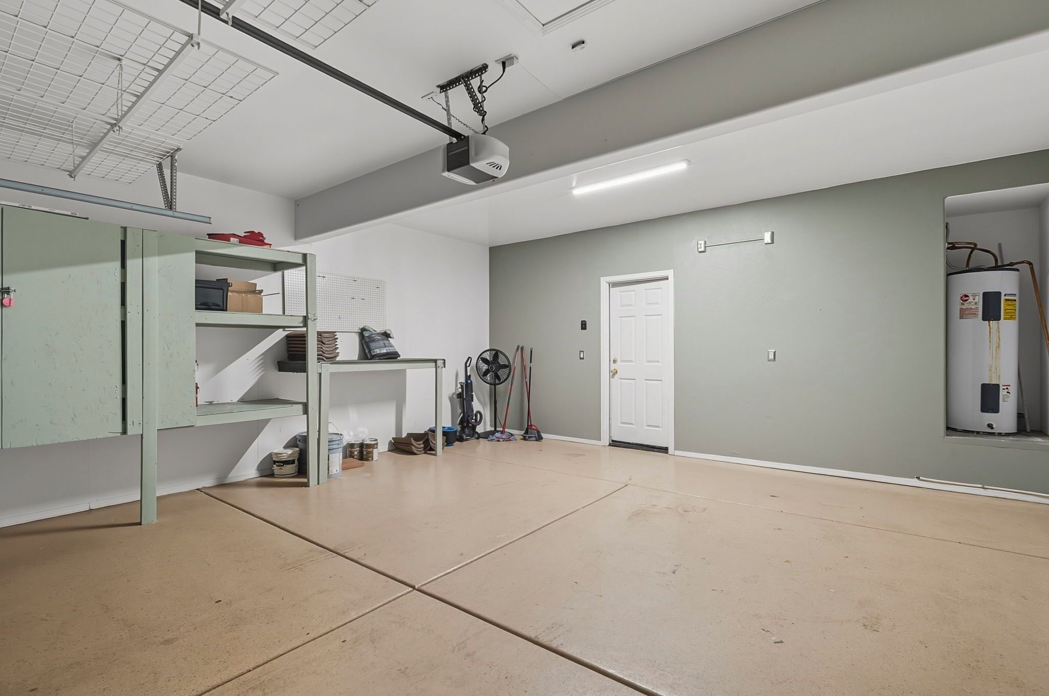 Tilava huone, jossa on valkoinen katto, projektori, vedenlämmitin ja ovi.