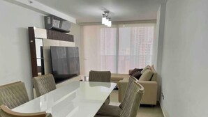 A modern living room with a dining table, chairs, a sofa, and a TV. - Cozy apartment in Panama (Panamá)