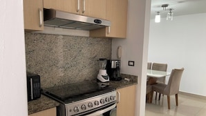 A compact kitchen with a stove, microwave, and coffee maker. - Cozy apartment in Panama (Panamá)