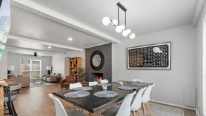 A modern dining area with a dark wooden table, white chairs, and a fireplace. - Spacious 8BR Modern Retreat Pool Table RV (Bethany)