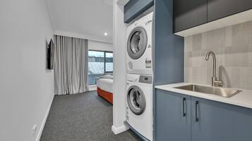 A modern hotel room with a washing machine, a sink, and a bed.