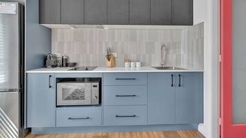 A modern kitchen with grey cabinets, a white countertop, and a built-in microwave.