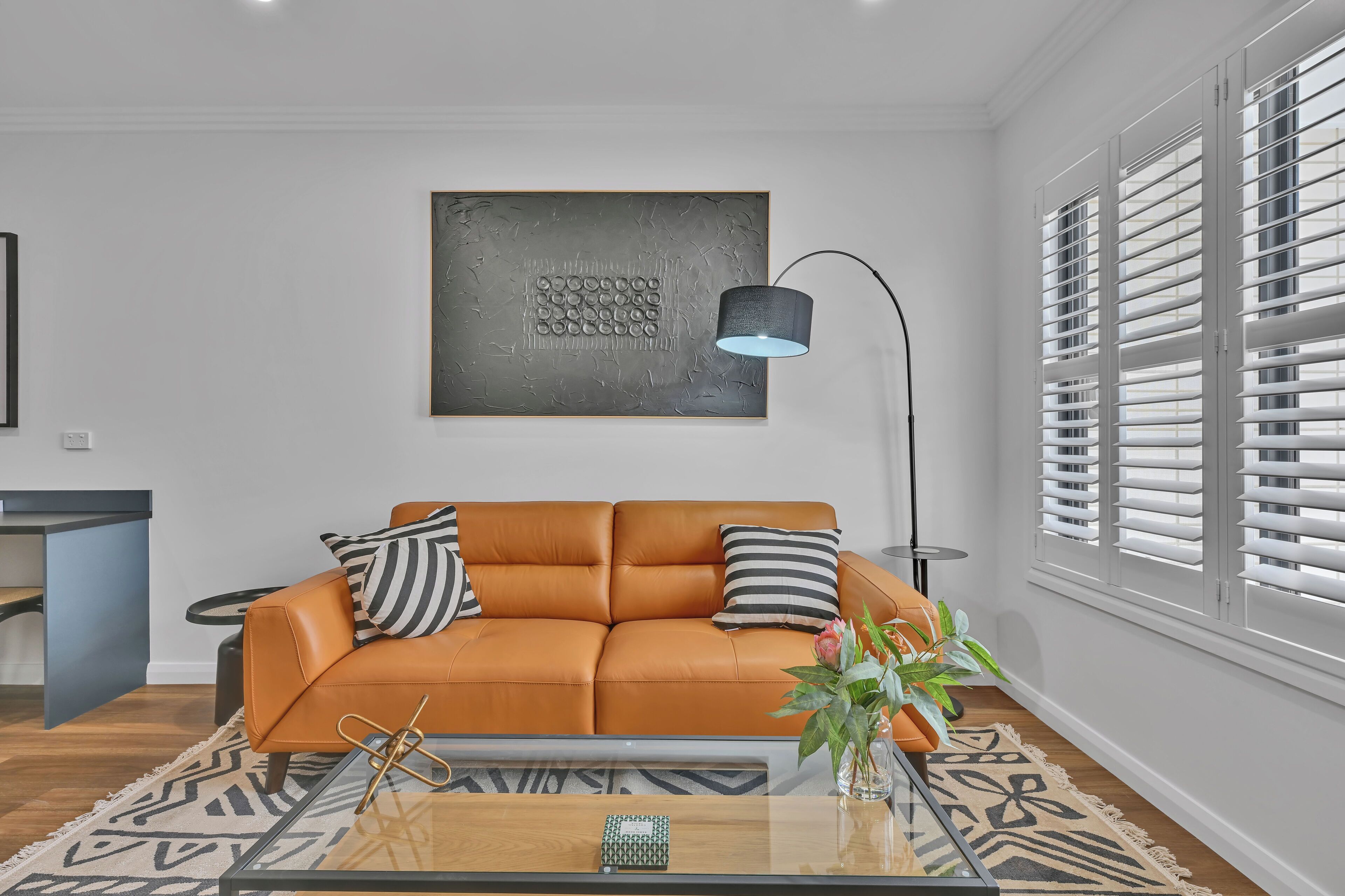 Ein modernes Wohnzimmer mit einer Ledersofa, einem Glastisch und einer zeitgemäßen Lampe.