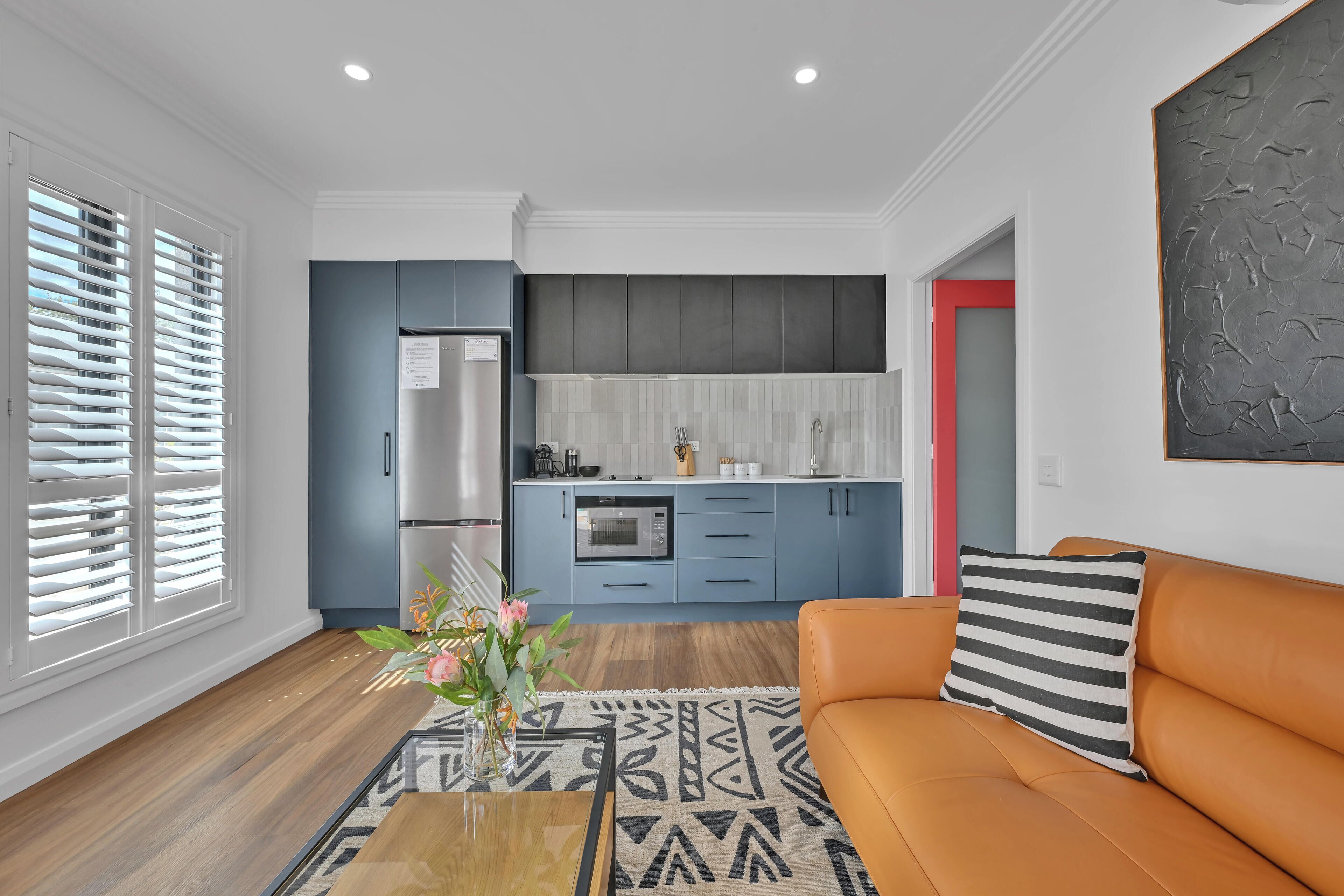 A modern kitchen with blue cabinets, a stainless steel refrigerator, and a microwave.