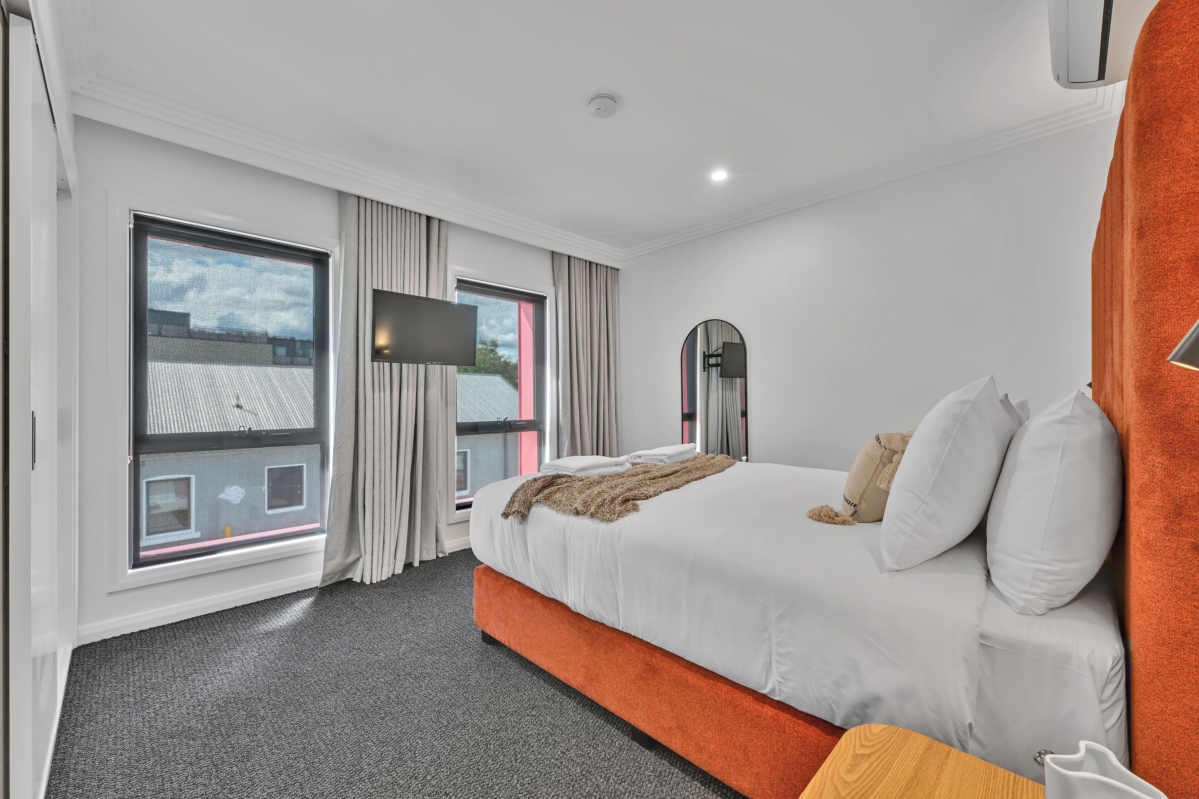 Una habitación de hotel moderna con una cama grande, un televisor de pantalla plana, una ventana con cortinas y vistas a la ciudad.