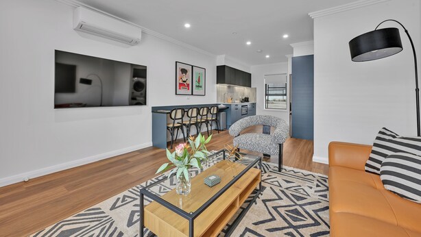 A modern living room with a sofa, coffee table, and a patterned rug. - The Mac Orange (Orange)