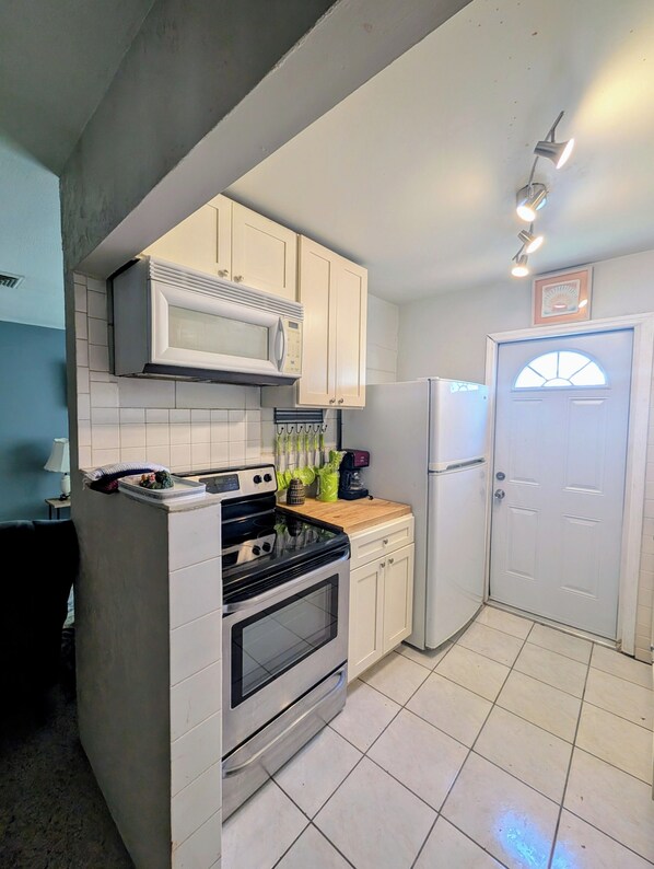 Kitchen features a stainless steel oven, microwave, and refrigerator, with a coffee maker and other essentials on the countertop.