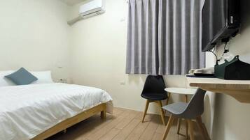 Een slaapkamer met een bed, bureau, stoel en televisie.