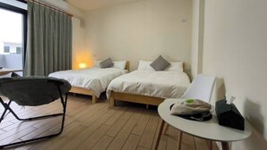 Ein Hotelzimmer mit zwei Einzelbetten, einem kleinen Tisch mit Stuhl und einer Klimaanlage über dem Fenster.