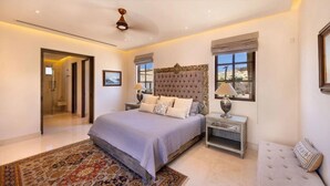 Une chambre avec un grand lit, des tables de chevet, un tapis à motifs et une vue sur l’extérieur.
