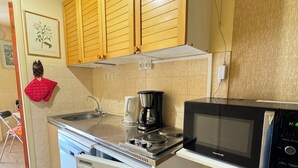 A compact kitchen with a refrigerator, stove, microwave, and wooden cabinets. - Appt Confortable in Superdévoluy (Le Dévoluy)