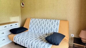 A bedroom with a sofa bed, a bedside table, a lamp, and a wall clock. - Appt Confortable in Superdévoluy (Le Dévoluy)