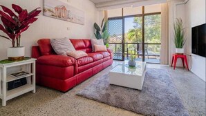 Una sala de estar moderna con un sofá rojo, una mesa de centro y un ventilador de techo.