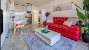 Una sala de estar moderna con un sofá rojo, una mesa de centro y un comedor con una mesa y sillas.