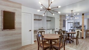 A modern kitchen with white cabinets, a wooden dining table with chairs, and a unique chandelier. - Beautiful condo in central Scottsdale (Scottsdale)
