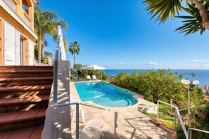 Ein Pool mit Stufen, umgeben von Grünpflanzen und mit Blick auf das Meer.