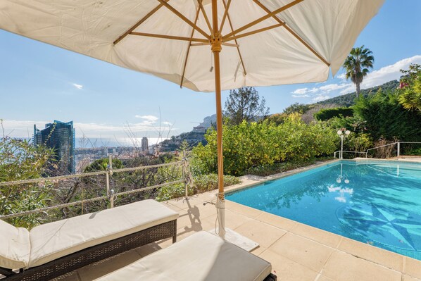 Ein Poolbereich mit Blick auf eine Stadtansicht, darunter ein hohes Gebäude.