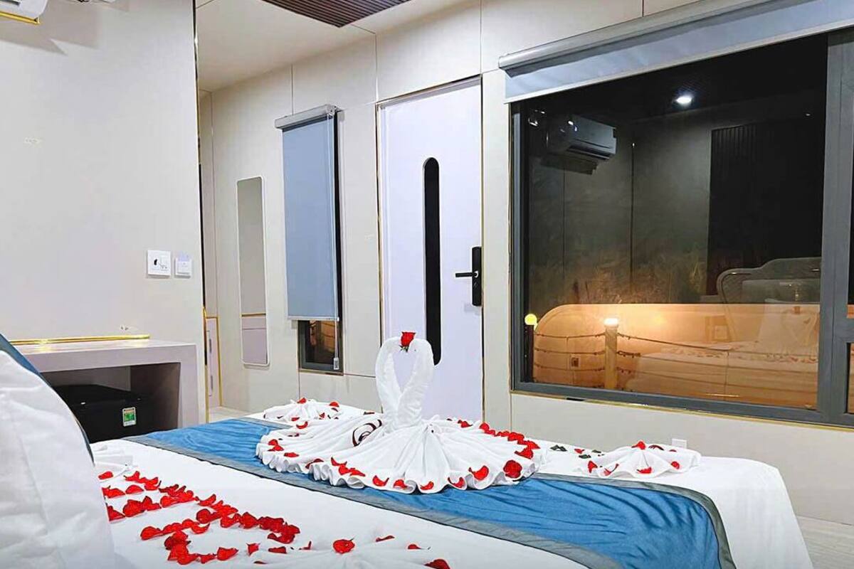Quarto de hotel com cama decorada com pétalas de rosas e um enfeite de cisne branco.