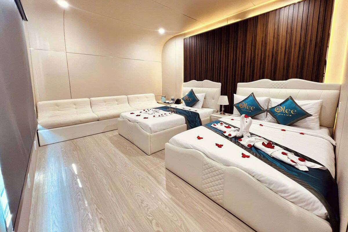 Quarto de hotel moderno com uma cama grande, um sofá e uma área de estar separada.