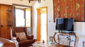 Un salón con muebles de cuero, una mesa de madera, un televisor y un adorno en la pared.