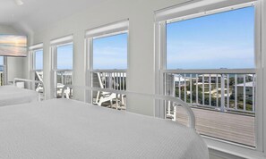 Habitación de hotel con balcón, ventanas amplias y vista al mar.