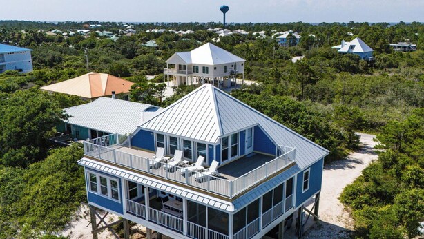 Een huis aan de kust met een groot terras, meerdere verdiepingen en een opvallende toren.