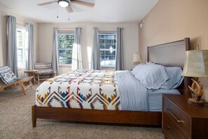 A bedroom with a bed, a nightstand, a lamp, a chair, and a window.
