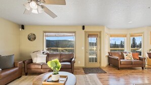 A spacious living room with two leather sofas, a wooden coffee table, and a ceiling fan. - Aurora Panorama Lodge- Perfect Retreat 5b3b (Fairbanks)
