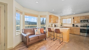 A spacious kitchen with a central island, wooden cabinets, and a stainless steel oven. - Aurora Panorama Lodge- Perfect Retreat 5b3b (Fairbanks)