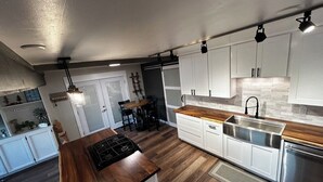 A modern kitchen with white cabinets, a wooden countertop, stainless steel appliances, and pendant lighting. - Charming 3-bedroom lake view home in tranquil Coeur d'Alene (Coeur d'Alene)