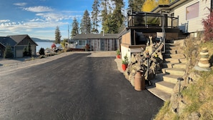 A residential property with a driveway leading to a house with a large window and a balcony. There are potted plants and a stone wall with a stacked stone arrangement. - Charming 3-bedroom lake view home in tranquil Coeur d'Alene (Coeur d'Alene)