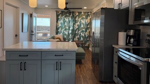 A modern kitchen with grey cabinets, a stainless steel refrigerator, and a built-in microwave. - Oceanfront Hideaway with Detached Primary Bedroom (Ewa Beach)