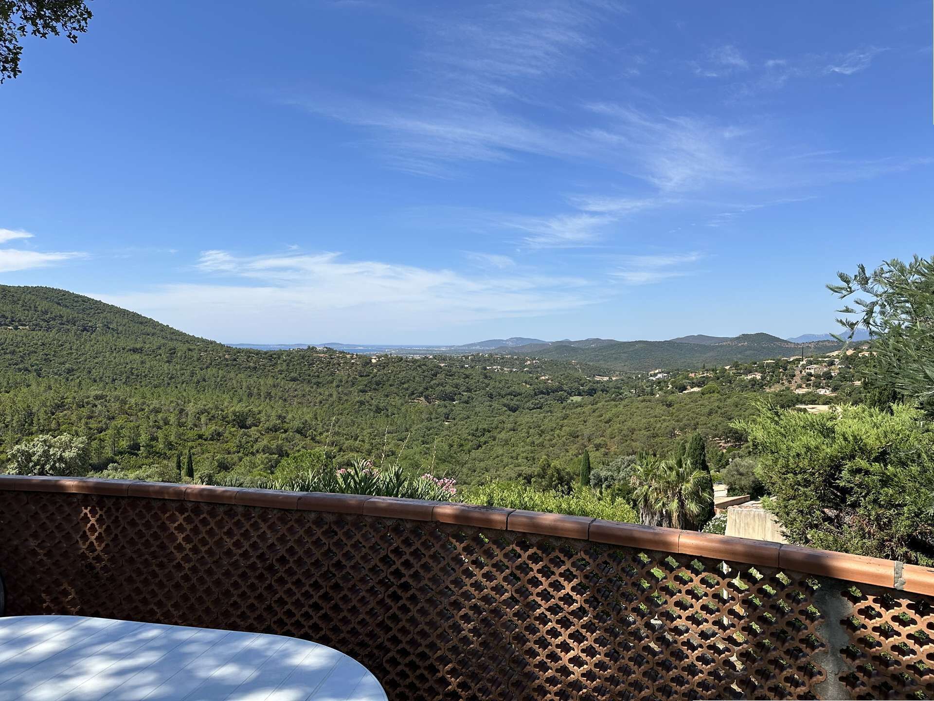 Um terraço com vista para uma paisagem montanhosa, um grade e uma mesa.