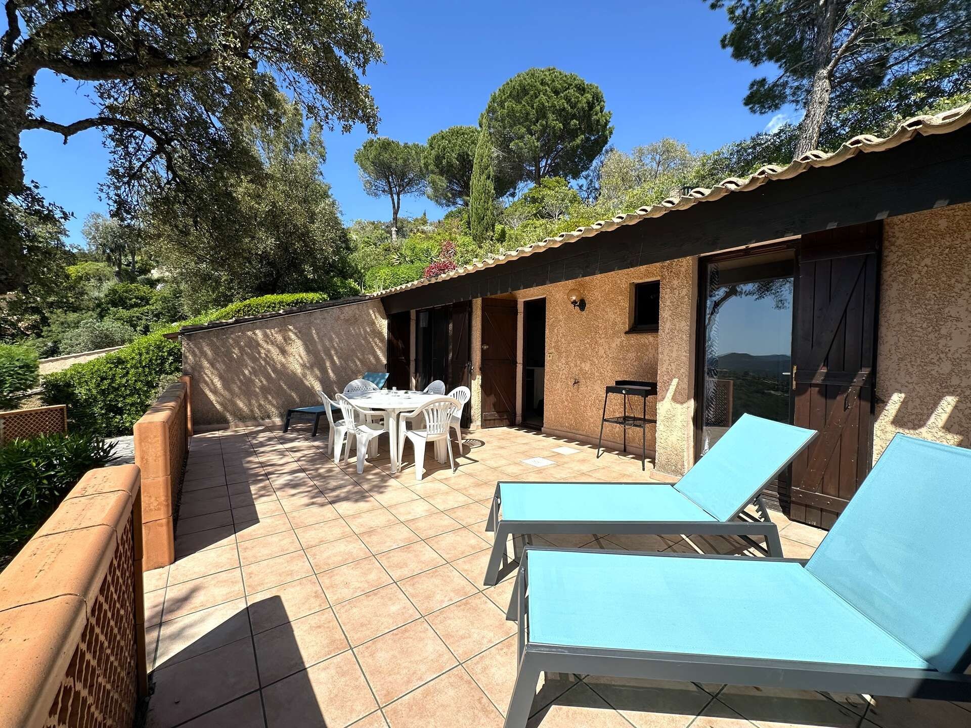 Een terras met een tafel en stoelen, een lounge stoel en uitzicht op het omliggende landschap.