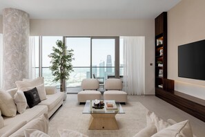 A modern living room with a sofa, two armchairs, a coffee table, and a large TV. - Maison Privee Sky-High Elegance w/ Unrivaled Burj Khalifa Views (Dubai)